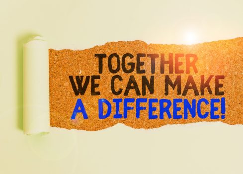 Writing note showing Together We Can Make A Difference. Business concept for be very important some way in like team or group Cardboard which is torn placed above a wooden classic table